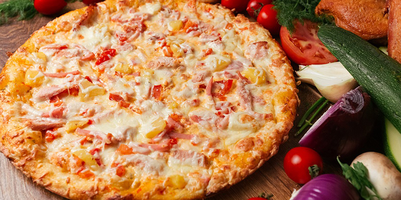 Готовая пицца на столе со свежими овощами