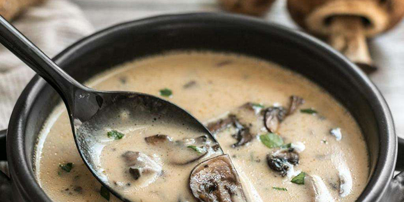 Чесночно-грибной суп в тарелке, а рядом сухие грибы